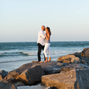 Couple standing on the rocks at the beach at sunset